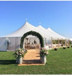 a large white tent set up with flowers and greenery