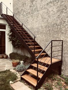 there is a metal stair case next to the wall with plants growing on it,