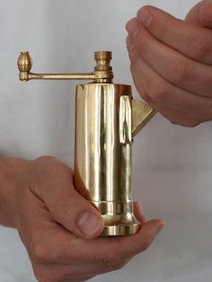 a person holding a gold colored lighter in their hand and the other hand is pointing at it