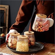 a person holding jars filled with food on top of a table