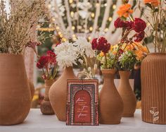 several vases with flowers in them sitting on a table next to a card holder