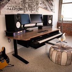 a computer desk with two monitors, keyboard and guitar in front of a large window