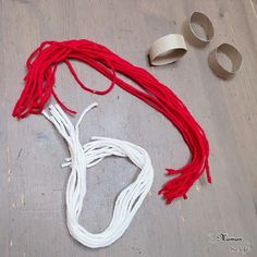 the red and white string is on the floor next to two silver objects that look like scissors