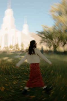 a blurry image of a woman walking through the grass in front of a building