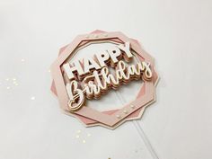 a pink and gold happy birthday sign sitting on top of a table