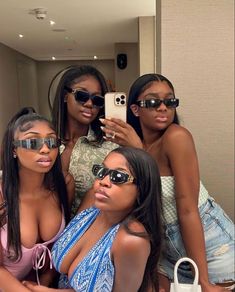 four beautiful young women taking a selfie in front of a mirror with their cell phone