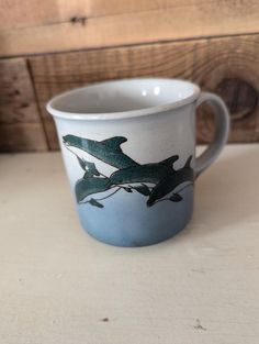 a blue and white coffee cup with two dolphins on the bottom, sitting on a table