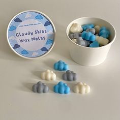 a cup filled with blue and white candies next to a container of cloudy skies wax melts