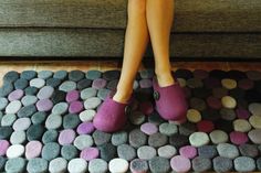 a woman's feet in slippers standing on a rug made out of rocks