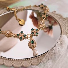 It's hard not to give in to the charm of the "Penelope" choker, designed to amaze and enchant those who watch you wear it, incredulous in the face of such splendor. Made with 14k gold-plated brass components embellished with splendid cubic zirconia crystals, emerald green dominates the scene and alternates with luminous crystals with refined shapes. The main pendant consists of an emerald green teardrop connector and a Mallorca teardrop pearl. The chain is made of 14k gold plated stainless steel Elegant Dangle Emerald Necklace Gift, Vintage Jeweled Choker As Gift, Vintage Jeweled Choker Gift, May Birthstone Party Jewelry, Emerald Necklaces With Jewels For Party, Green Clavicle Chain Necklace For Wedding, Emerald Jeweled Necklaces For Party, Elegant Green Dangle Necklace, Green Metal Choker For Party