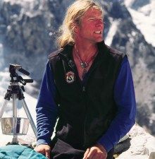 a man sitting on top of a mountain next to a camera