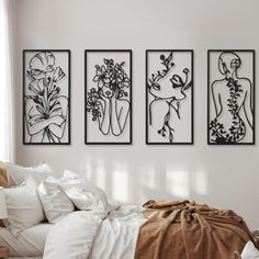 three black and white artwork hanging on the wall above a bed