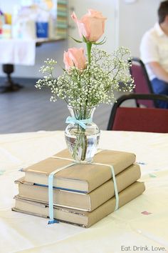 a vase filled with pink roses sitting on top of two books next to each other