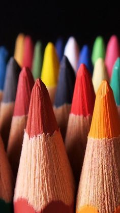 many colored pencils are lined up in rows