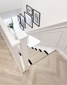 an overhead view of a staircase with pictures hanging on the wall and wooden flooring