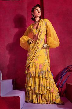 Yellow pre-draped saree with all-over floral print and layered ruffle trim on the hem. Comes with V neck bugle bead embroidered blouse.
Component: 2
Pattern: Print and Embroidery
Type Of Work: Floral Print, Beads and Bugle Beads
Neckline: V neck
Sleeve Type: Puff Sleeves
Fabric: Georgette
Color: Yellow
Other Details: 
Sheer puff sleeves with scalloped detail cuffs
Cuffs with tie up
Closure: Side zip
Note: Choker worn by the model is not for sale
Occasion: Sangeet - Aza Fashions Co Ords Outfits, Draped Saree, Delhi Wedding, Lehenga Wedding, Drape Saree, Yellow Saree, Beaded Neckline, Blouse For Women, Indian Fashion Designers