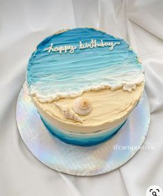 a blue and white birthday cake with seashells on it that says happy birthday