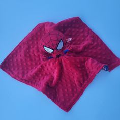 a red spider - man blanket laying on top of a blue surface with the eyes open