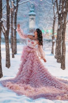 a woman in a pink dress standing in the snow