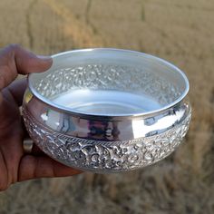 a person holding a silver bowl in their hand