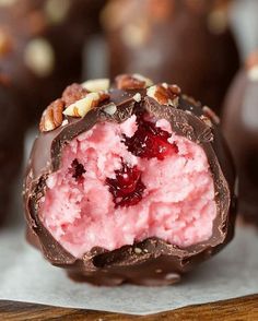 there is a piece of chocolate covered in pink and white ice cream with nuts on top