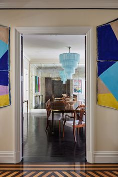 an open door leading to a dining room with chairs and a chandelier hanging from the ceiling