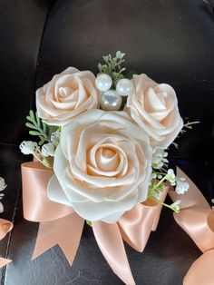 a bridal bouquet with roses and pearls on the back of a black car seat