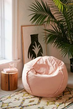 a pink bean bag chair sitting on top of a rug next to a potted plant