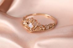 a gold ring with an opal stone in the middle on a pink satin background