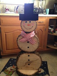 a snowman made out of logs sitting on top of a kitchen floor