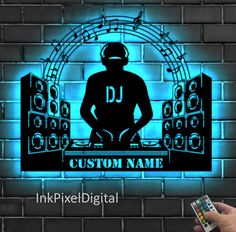 a person holding a remote control in front of a brick wall with a dj logo on it