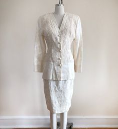 "Ivory floral jacquard and lace matching suit set, from the 1980s. Jacket measures 18\" (46 cm) flat across bust, 15\" (38 cm) flat across waist, and is 28\" (71 cm) long. Jacket has shoulder pads. Skirt measures 13.5\" (34 cm) flat across waist, 19.5\" (49.5 cm) flat across hips, and is 26\" (66 cm) long. Cotton and acetate. Original size is a 4. By Jessica McClintock." Formal Fitted Lace Sets, Fitted Lace Trim Set For Wedding, Fitted Cream Lace Sets, Cream Lace Fitted Sets, White Lace Formal Sets, Fitted Vintage White Sets, Vintage Fitted Long Sleeve Sets, Fitted Vintage Set With Lace Trim, Fitted Vintage Sets With Lace Trim