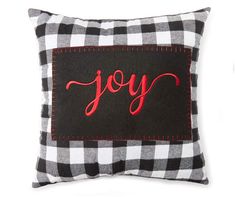 a black and white plaid pillow with the word joy embroidered on it's side