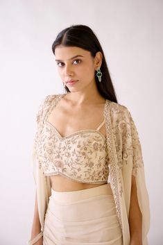 Stunning ivory embroidered ruched skirt set with cape is an effortless festive wear. It is crafted in georgette, organza and silk fabric. Shop online from Pure Elegance. Disclaimer: The actual product may vary slightly from the image. These are custom orders, hence expect slight variation in color and placement of the motif or buta. ESTIMATED DELIVERYBecause this is a custom order, it would take about 4 weeks from the date of purchase. RETURN POLICYThis product is a custom order and cannot be returned or exchanged. Embroidered Lehenga With Cape Sleeves In Organza, Embroidered Organza Lehenga With Cape Sleeves, Embroidered Blouse Piece With Cape Sleeves For Wedding, Evening Embroidered Choli With Cape Sleeves, Embroidered Choli With Cape Sleeves For Evening, Organza Choli With Cape Sleeves For Reception, Party Beige Georgette Dupatta, Party Cream Georgette Dupatta, Cream Georgette Sets For Reception