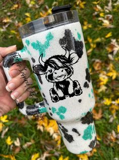 a person holding a cup with a cow on it