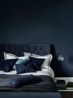 a bedroom with dark blue walls and white bedding, along with a black headboard