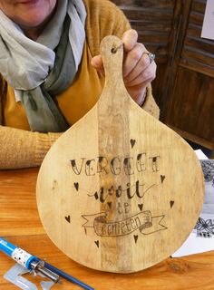 a woman is holding a wooden spoon with writing on it