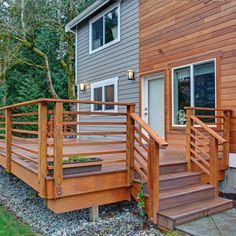 a wooden deck with steps leading up to the front door and side of a house