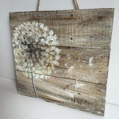 a dandelion painted on wood hanging from a rope with string attached to it