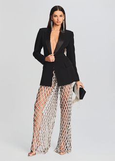 a woman in a black jacket and fishnet pants with her hand on her hip