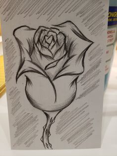 a black and white drawing of a rose on a piece of paper with writing underneath it