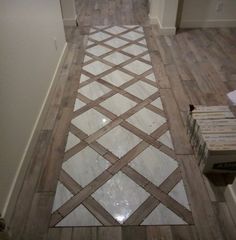 a white and brown tile floor in a room with wood floors on one side and wooden parquets on the other