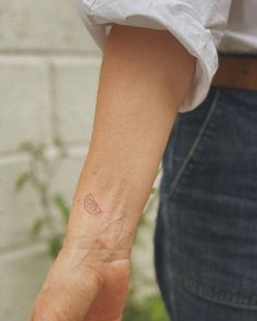 a person with a small tattoo on their left wrist holding onto another persons hand and looking at the camera