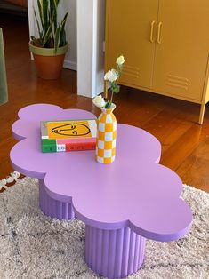 a purple coffee table with a flower in a vase on top of it and some books