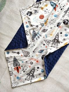 two baby swaddles laying next to each other on top of a bed covered in space themed sheets