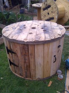 a large wooden barrel sitting on top of a lush green field