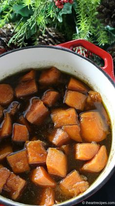 a pot filled with stew sitting on top of a table next to pine cones and evergreen needles