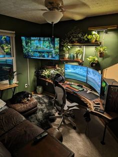 a living room filled with lots of furniture and two computer monitors on top of a desk