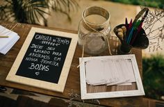 a wooden table topped with a chalkboard next to a glass jar filled with writing