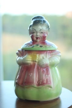 Vintage 1950s "Aunt Bee" Cookie Jar. Granny /Auntie is holding a cookie in a bun and green dress with a pink apron that ties in a big bow in the back. Excellent vintage condition. There are two white marks that are very small and appear to be a flaw in the glaze at manufacturing and not damage. These American Bisque cookie jars are treasured collectables and this is a very well preserved find! Approximately 13" tall and 7 " wide and about 2 kegs in weight. Bee Cookies, Turtle Cookies, Pink Apron, Cookie Jars Vintage, Kitchen Jars Storage, Big Bow, White Mark, Jar Containers, Cookie Jars